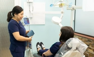 Dental assistant speaking with a seated patient before treatment